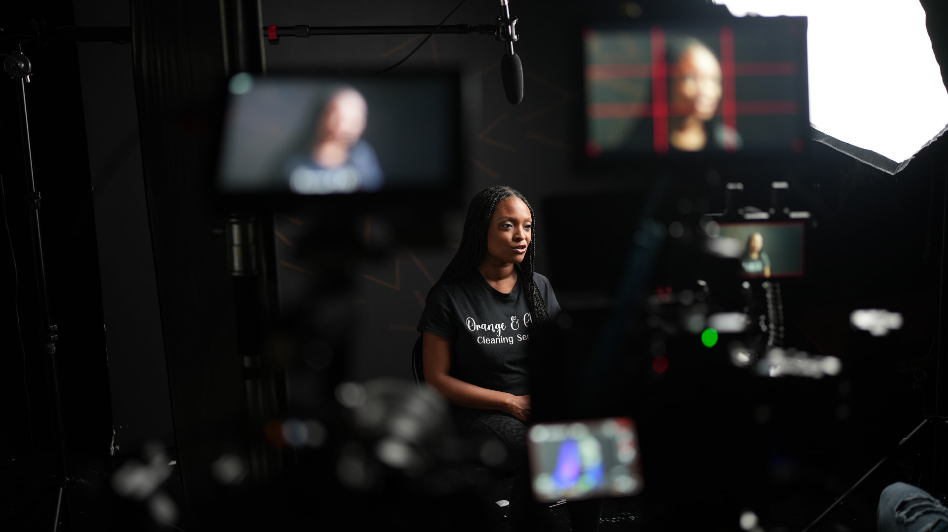 Business owner being interviewed on a moody dark studio set with monitors